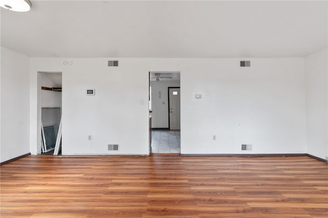 unfurnished room with built in shelves and hardwood / wood-style floors