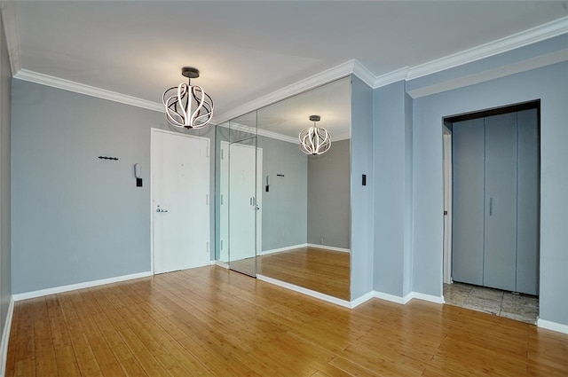 spare room with ornamental molding, hardwood / wood-style floors, and a chandelier