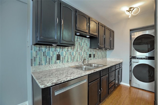 kitchen with backsplash, stacked washer and dryer, sink, light hardwood / wood-style floors, and stainless steel dishwasher