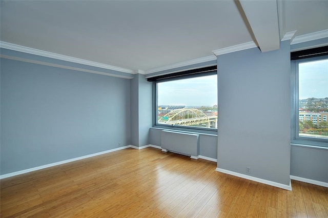 spare room with ornamental molding, a wealth of natural light, radiator, and light hardwood / wood-style flooring