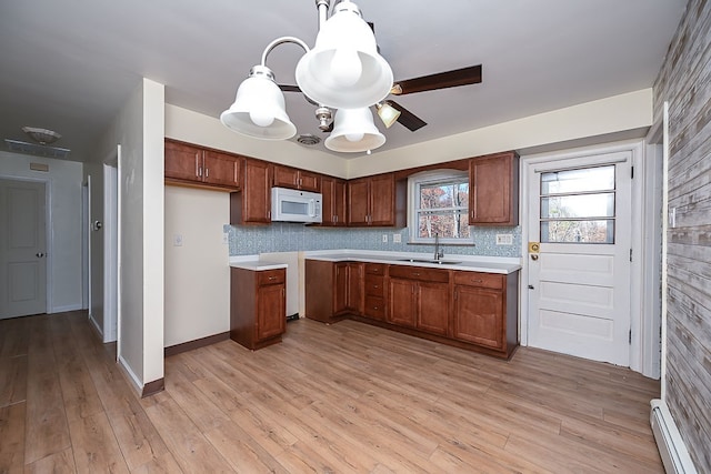 kitchen featuring a baseboard heating unit, light wood-type flooring, decorative backsplash, and pendant lighting