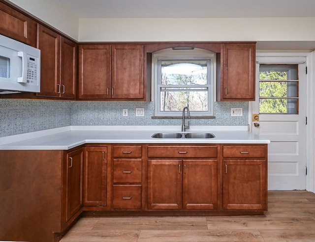 kitchen with light hardwood / wood-style floors, sink, and tasteful backsplash