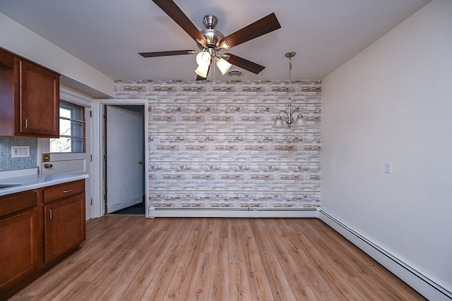 interior space featuring light wood-type flooring, ceiling fan with notable chandelier, and a baseboard radiator