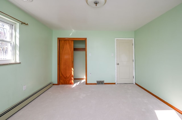 unfurnished bedroom featuring a closet, light carpet, and a baseboard heating unit