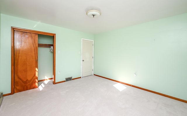 unfurnished bedroom with carpet flooring, a closet, and a baseboard heating unit