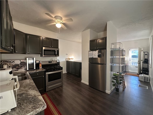 kitchen with a textured ceiling, stainless steel appliances, and dark hardwood / wood-style floors