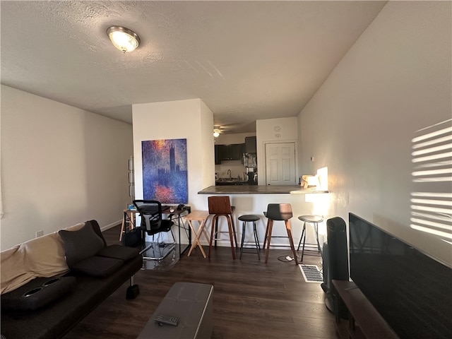 living room featuring ceiling fan, a textured ceiling, and dark hardwood / wood-style flooring