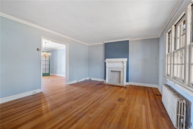 unfurnished living room with radiator heating unit, wood-type flooring, a notable chandelier, and crown molding