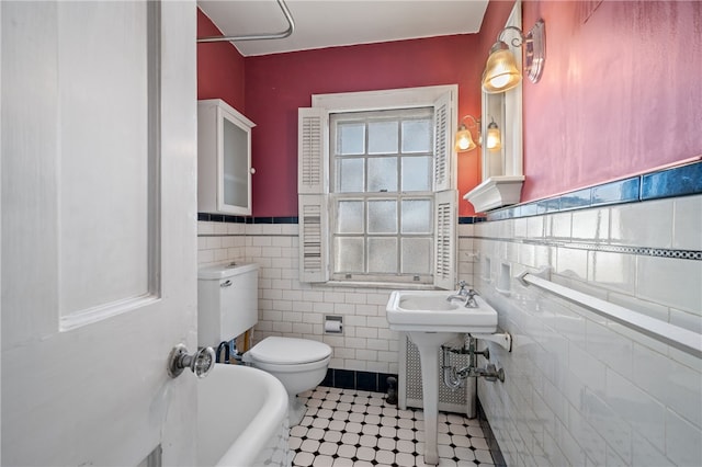 bathroom with toilet, a washtub, tile walls, and tile patterned floors