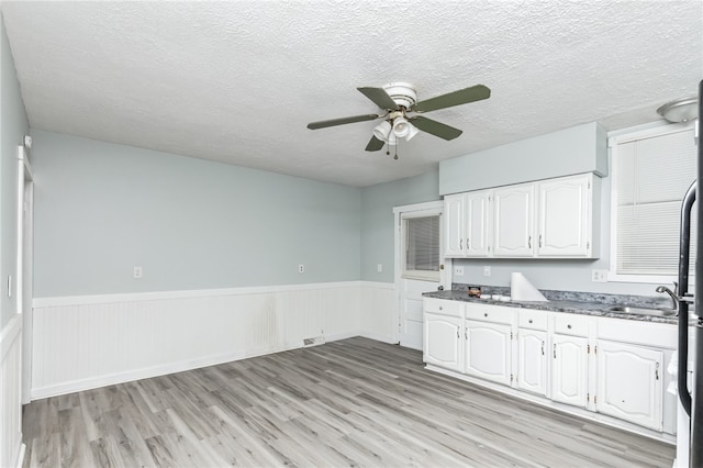 kitchen with white cabinets, a textured ceiling, sink, ceiling fan, and light hardwood / wood-style flooring