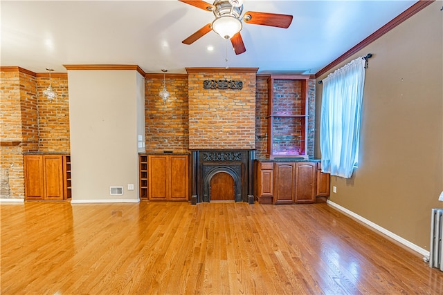 unfurnished living room with a fireplace, crown molding, light hardwood / wood-style floors, ceiling fan, and brick wall