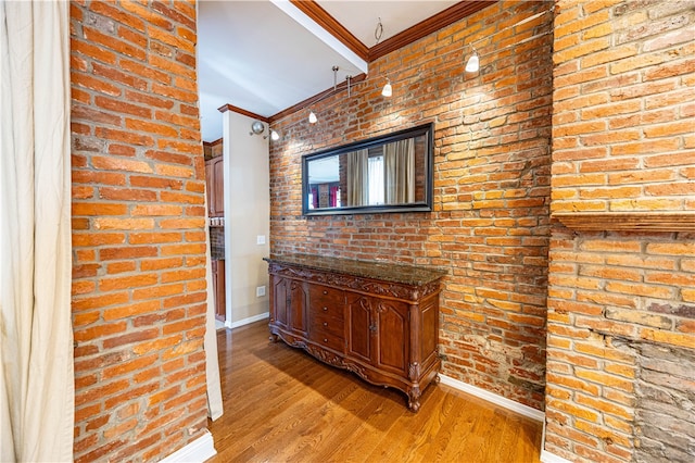 hall featuring light wood-type flooring, brick wall, and crown molding