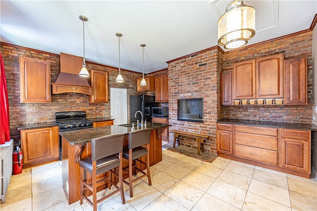 kitchen featuring a center island with sink, black appliances, a breakfast bar, brick wall, and premium range hood