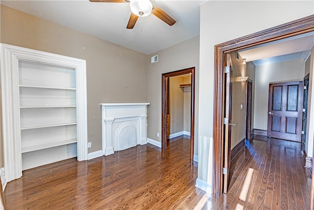 unfurnished living room with built in features, wood-type flooring, and ceiling fan