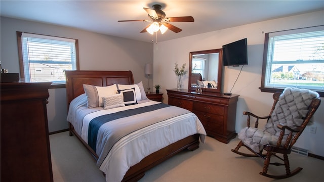 carpeted bedroom with multiple windows and ceiling fan