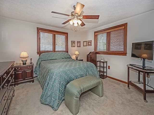 bedroom with a textured ceiling, light carpet, and ceiling fan