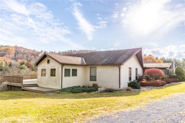 view of side of home with a wooden deck and a yard