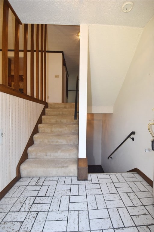 stairs with lofted ceiling and a textured ceiling