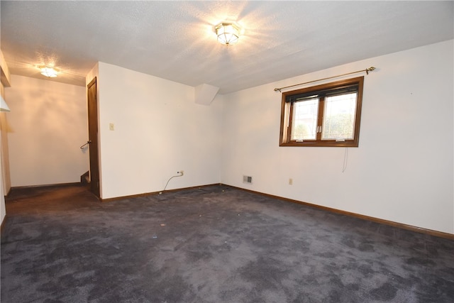 unfurnished room featuring a textured ceiling and dark colored carpet