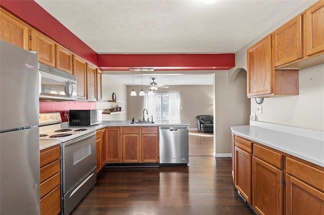 kitchen featuring stainless steel appliances, sink, kitchen peninsula, dark hardwood / wood-style floors, and pendant lighting