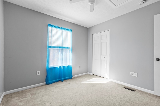 unfurnished bedroom with a closet, carpet, a textured ceiling, and ceiling fan