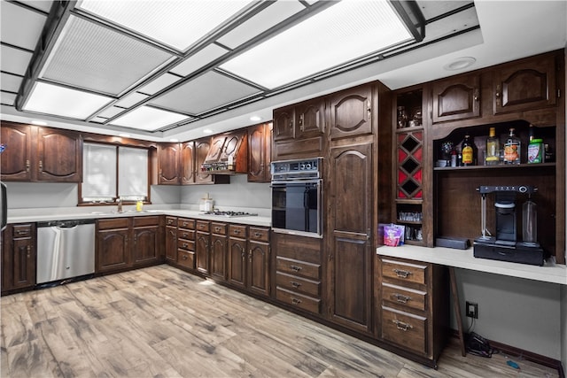 kitchen with dark brown cabinets, stainless steel appliances, and light hardwood / wood-style floors