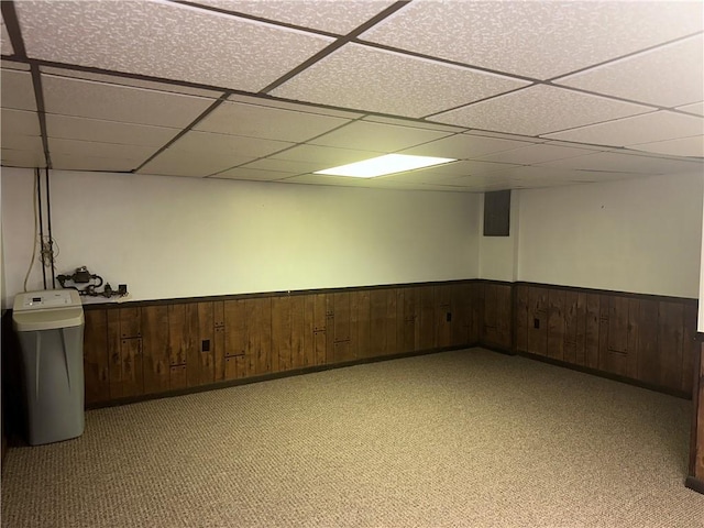 basement featuring a paneled ceiling and light colored carpet