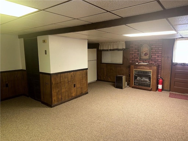 basement with a drop ceiling, white fridge, and light carpet