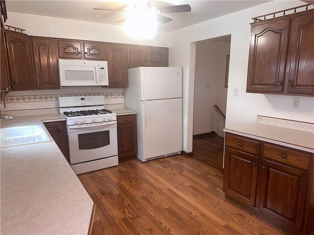 kitchen with white appliances, backsplash, dark wood-type flooring, sink, and ceiling fan