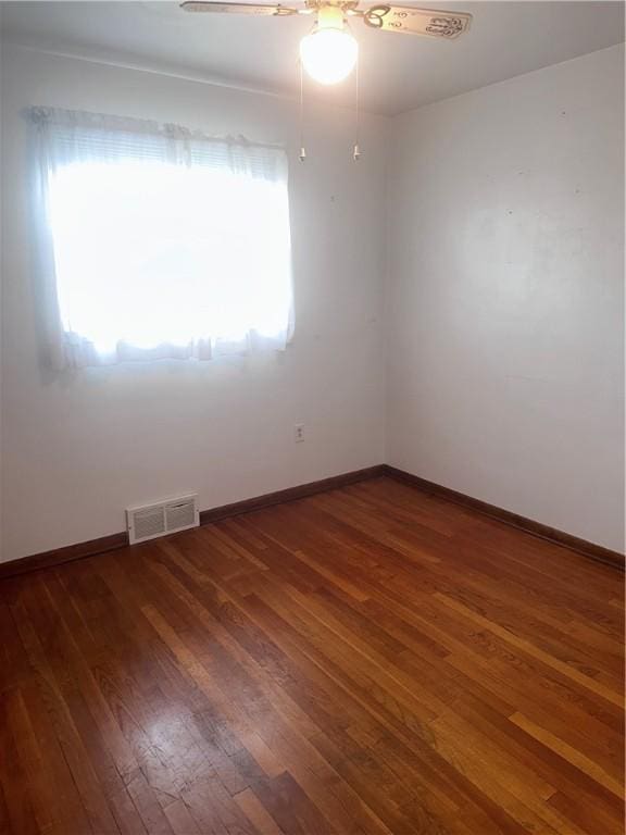 unfurnished room featuring plenty of natural light, dark wood-type flooring, and ceiling fan