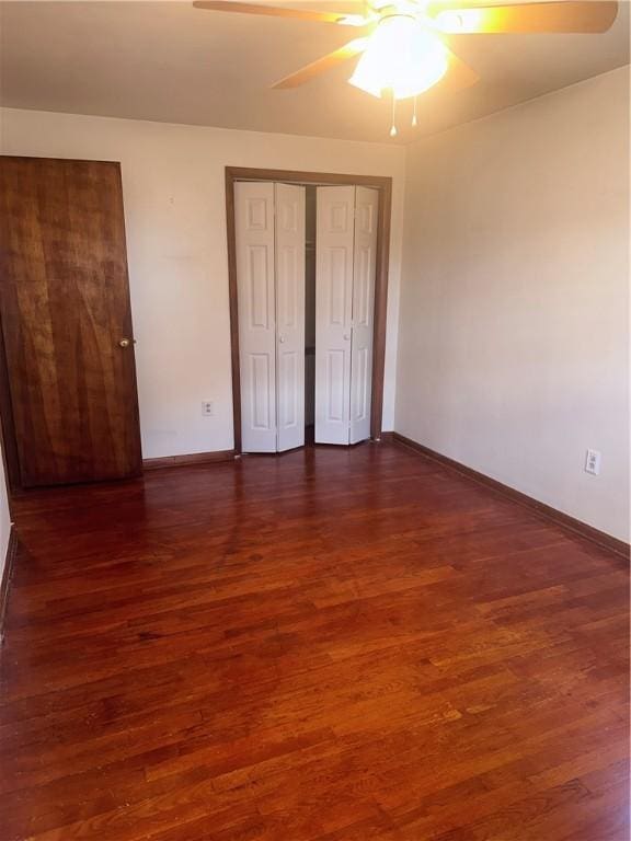 unfurnished bedroom with ceiling fan, dark wood-type flooring, and a closet