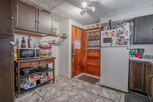 kitchen featuring dark brown cabinetry and white fridge