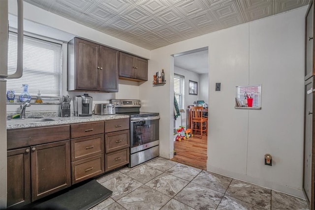 kitchen featuring sink, electric range, light stone countertops, dark brown cabinets, and light wood-type flooring