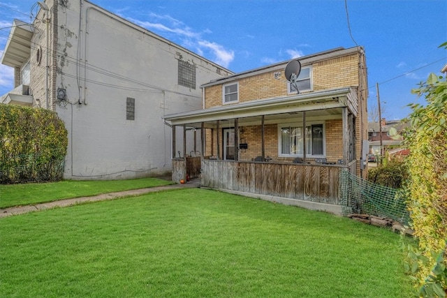 back of property with covered porch and a yard