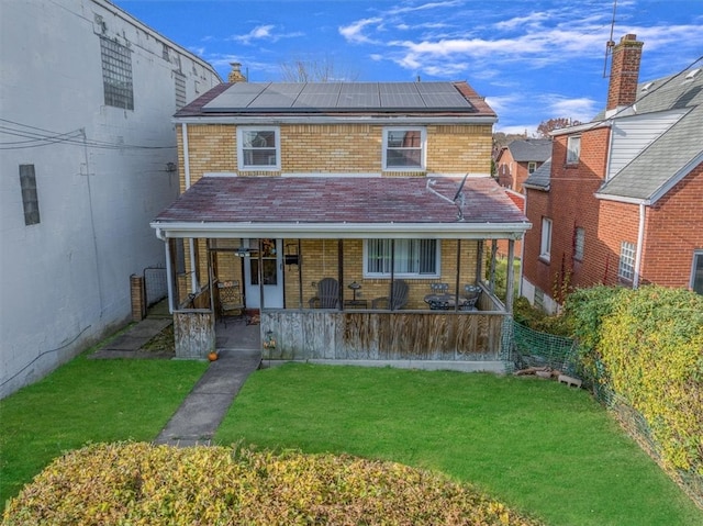 rear view of house featuring solar panels, a porch, and a yard