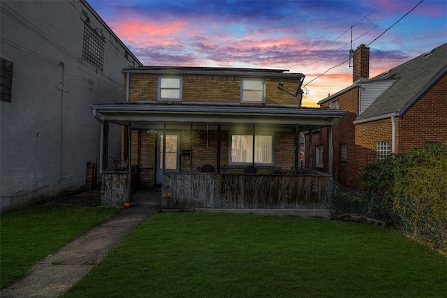 back house at dusk with a lawn and a porch