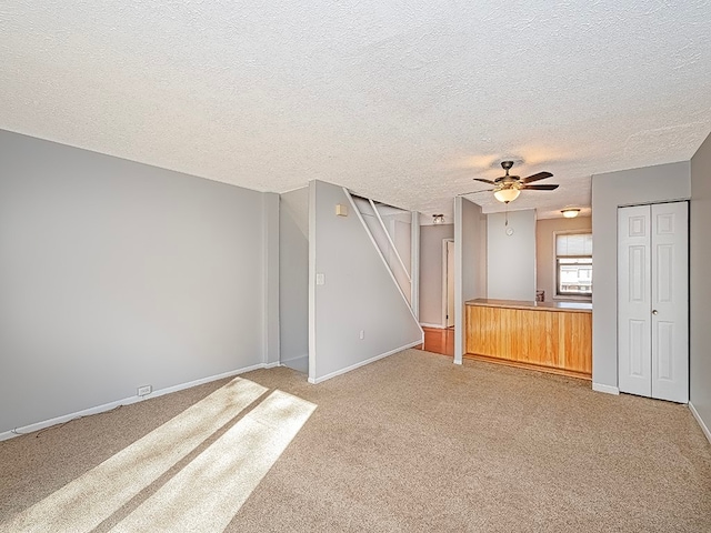 unfurnished living room featuring a textured ceiling, ceiling fan, and carpet floors