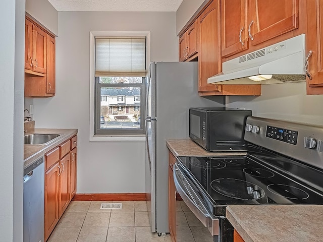 kitchen featuring a textured ceiling, appliances with stainless steel finishes, light tile patterned floors, and sink