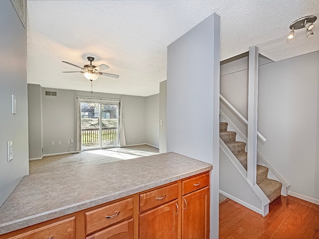 kitchen with a textured ceiling, light wood-type flooring, and ceiling fan