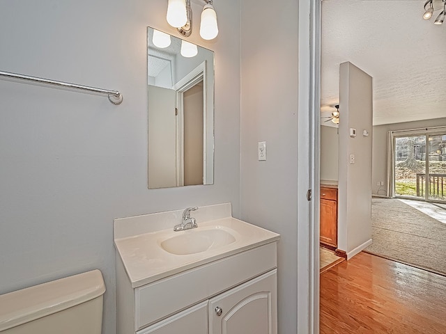 bathroom featuring vanity, wood-type flooring, a textured ceiling, and toilet