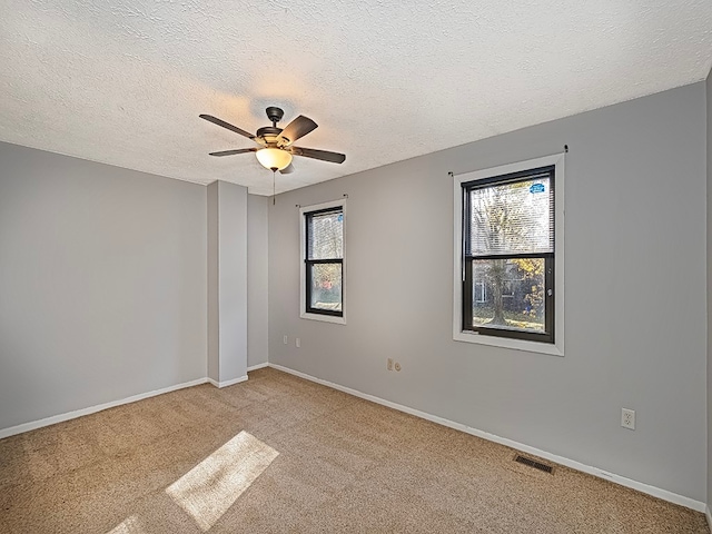 spare room with light colored carpet, a textured ceiling, and ceiling fan