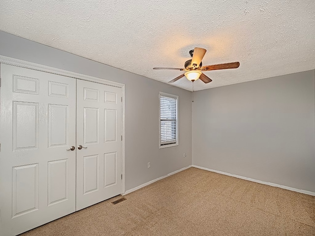 unfurnished bedroom with ceiling fan, a textured ceiling, a closet, and carpet floors