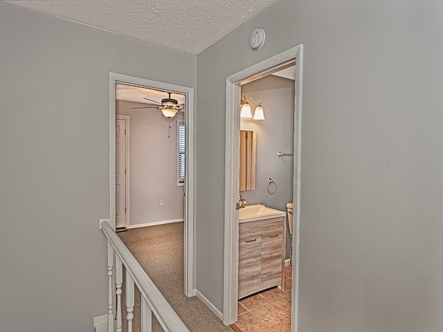 corridor featuring a textured ceiling, sink, and light tile patterned flooring