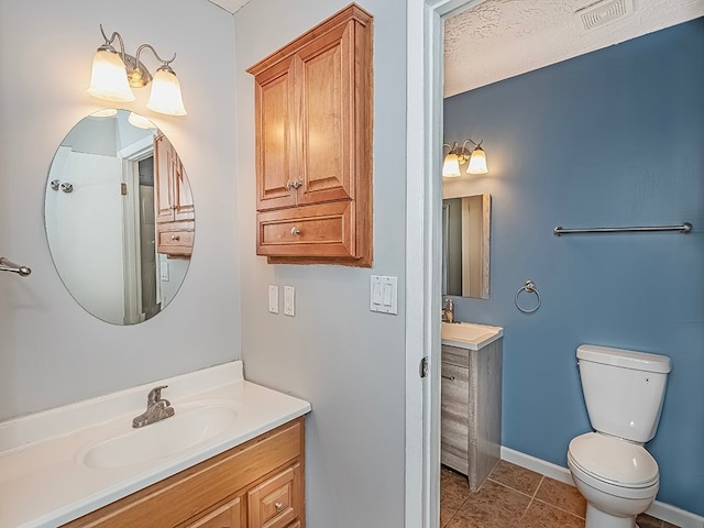 bathroom with toilet, vanity, a textured ceiling, and tile patterned flooring