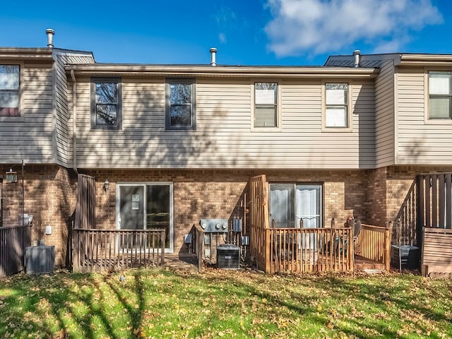 back of property with central AC unit and a yard