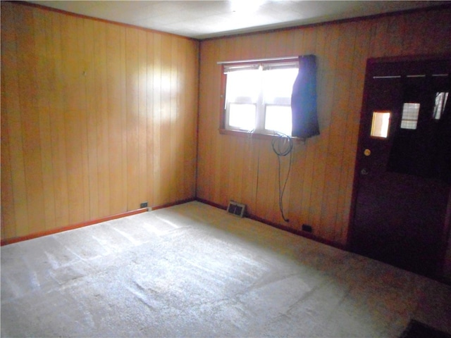 carpeted entryway with wood walls