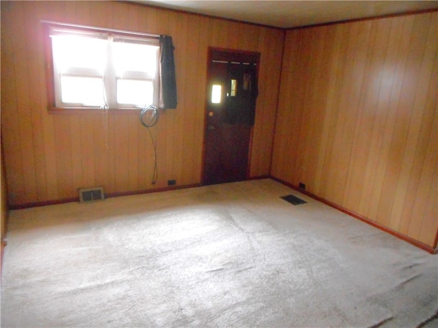 carpeted spare room with wooden walls