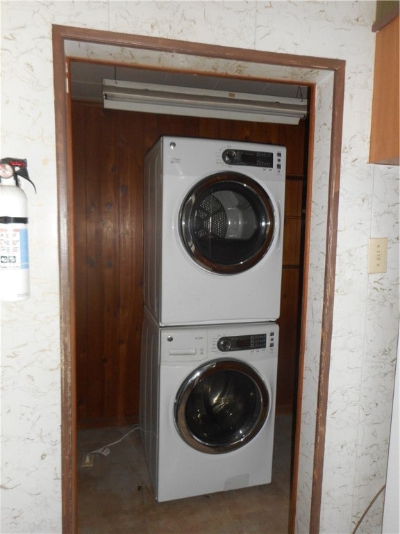 laundry room featuring stacked washer / dryer and wooden walls