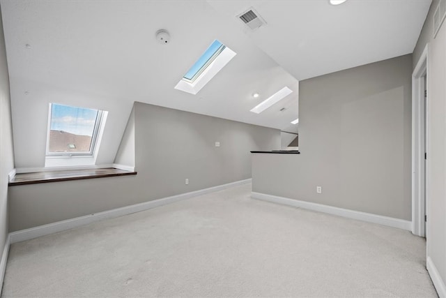 additional living space with vaulted ceiling with skylight and light carpet