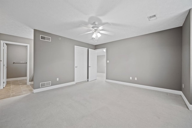 unfurnished bedroom with a textured ceiling, light colored carpet, and ceiling fan